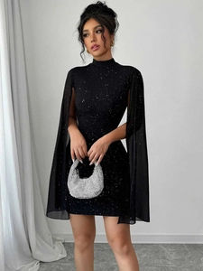 Detail eines schwarzen Kleids mit Sternenlicht-Glitzern und transparenten Cape-Ärmeln