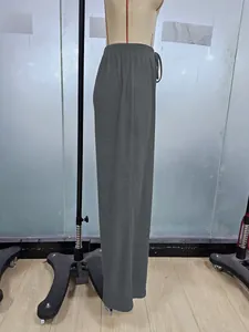 Dettaglio dei pantaloni plissettati grigio scuro a gamba larga con elastico in vita