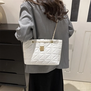 White quilted chain shoulder bag with gold hardware shown on a model in a stylish setting