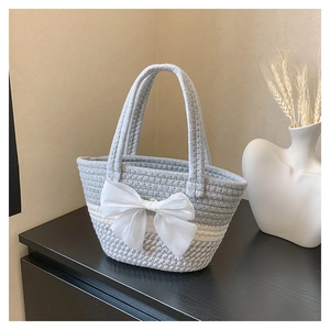 Dettaglio della borsa tote intrecciata a mano con strisce e fiocco decorativo in raso bianco