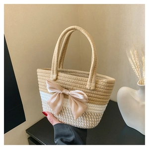 Dettaglio borsa in paglia intrecciata con grande fiocco di raso e trama bicolore elegante