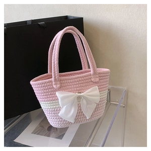 Dettaglio della borsa tote intrecciata rosa con un grande fiocco bianco e strisce
