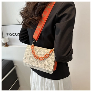 Detail of woven crossbody bag with green floral embroidery and orange Lucky logo strap