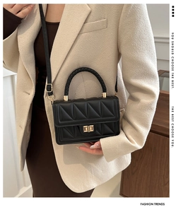 Detail of black quilted crossbody bag featuring woven handle and gold hardware on model