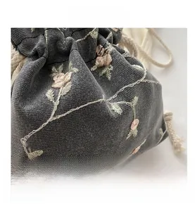 Detail of floral embroidery on grey mesh drawstring bag with soft cotton cord closure