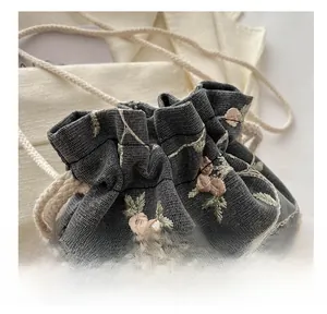 Detail of grey lace mesh bucket bag featuring floral embroidery and cotton drawstring