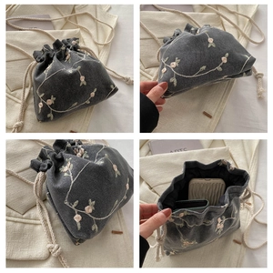 Vista dettagliata della mini borsa a secchiello grigia ricamata con lacci e capienza