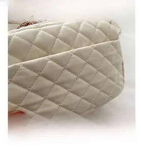 Close-up of quilted beige leather bag detailing fine texture and woven wide strap