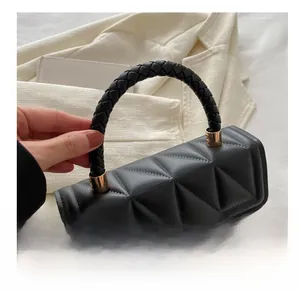 Close-up of black quilted handbag with geometric texture and woven leather handle