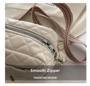 Macro shot of smooth metal zipper and quilted rhombus texture on the cream boston bag