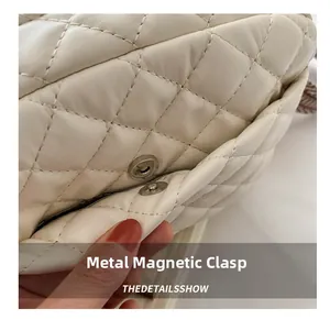 Close-up of metal magnetic snap and quilted leather texture on cream small square bag