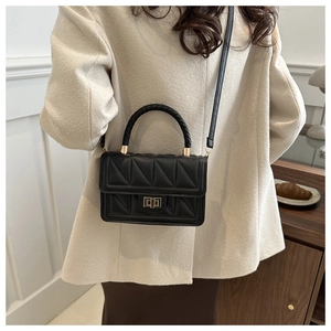 Detail of black quilted shoulder bag with golden twist lock and woven handle