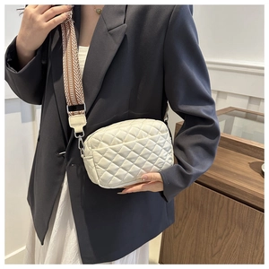 Detail of white quilted crossbody bag with stylish wide herringbone woven strap