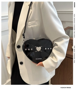 Détail du sac à bandoulière noir en forme de cœur avec clous argentés et boucle métal