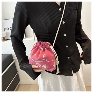 Dettaglio di ricamo floreale rosa su una mini borsa a secchiello con coulisse da donna