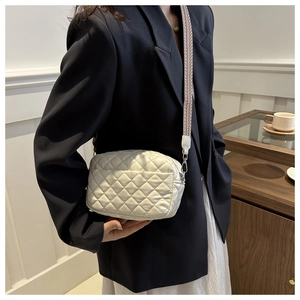 Detail of white quilted crossbody bag with stylish wide patterned shoulder strap