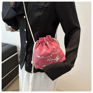 Detail of pink embroidered bucket bag with floral patterns and cotton rope shoulder strap