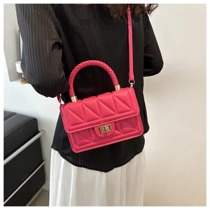 Detail of bright pink quilted square bag featuring chunky woven handle and gold metal lock