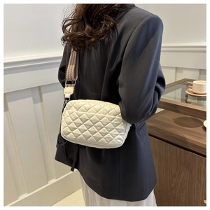 Detail of quilted rhombic pattern shoulder bag with a woven geometric strap design