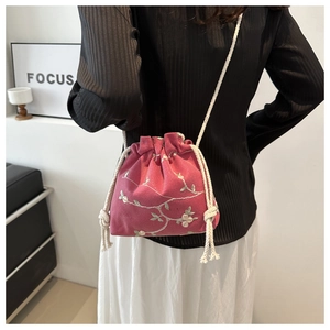 Detail of rose red drawstring bucket bag with white floral embroidery and cotton rope straps