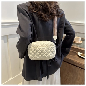 Detail of white quilted crossbody bag with stylish patterned wide shoulder strap