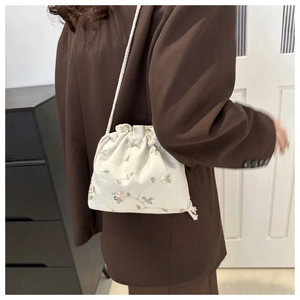 Dettaglio del ricamo floreale e della coulisse su una mini borsa a secchiello in tela
