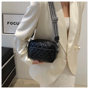 Close-up of black quilted small square bag with decorative geometric wide strap