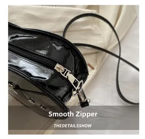 Détail de la fermeture éclair argentée et du cuir verni noir brillant sur le sac chic