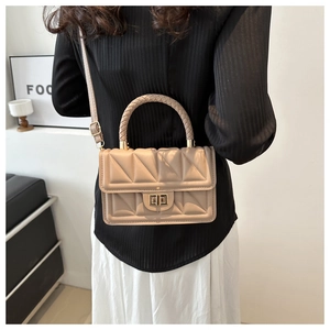 Detail of apricot quilted square bag with woven handle and metal twist lock closure