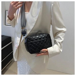 Close-up of quilted crossbody bag featuring a geometric wide strap and glossy finish