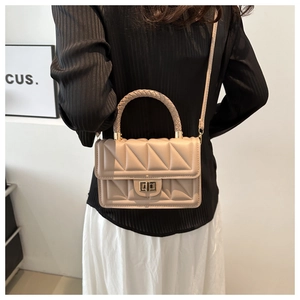 Detail of beige quilted square bag with gold twist lock and woven handle for women