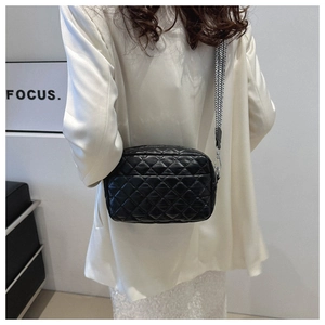 Detail of black quilted crossbody bag featuring a patterned wide fabric shoulder strap