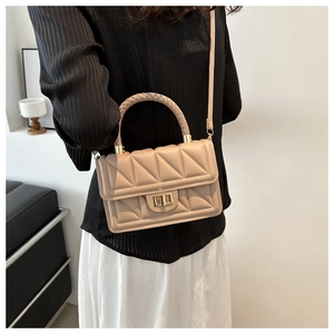 Close-up of beige quilted crossbody bag with gold-tone turn-lock and woven handle