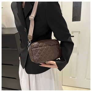 Detail of dark brown quilted crossbody bag with wide geometric patterned strap