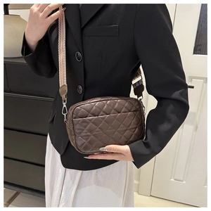 Detail of a dark brown quilted crossbody bag featuring a stylish geometric wide strap
