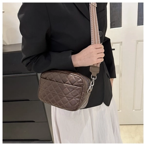 Close-up of brown quilted crossbody bag featuring a retro diamond lattice and wide strap