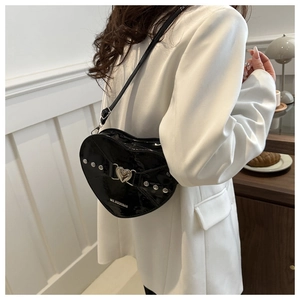 Gros plan d'un sac cœur en cuir verni noir avec des rivets et une boucle métallique