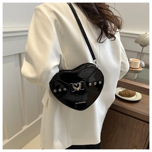 Vue latérale d'un sac cœur en cuir verni noir avec clous porté par un mannequin