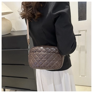 Detail view of brown quilted crossbody bag with stylish jacquard woven wide shoulder strap