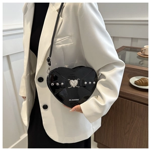 Détail d'un sac à bandoulière noir en forme de cœur avec rivets argentés et fermoir