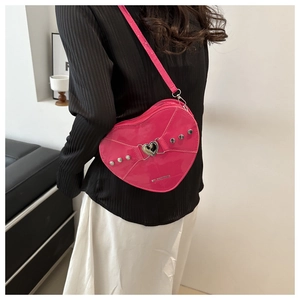 Détail d'un sac à bandoulière rose fuchsia en forme de cœur avec clous argentés