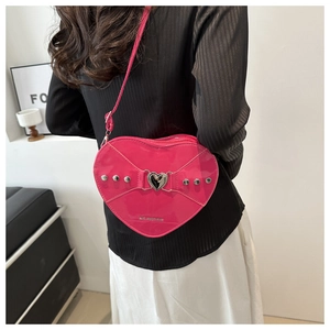 Gros plan d'un sac à main en cuir verni rose en forme de cœur avec rivets et boucle métal