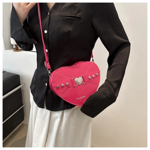Détail du sac bandoulière rose en forme de cœur avec rivets et logo de la marque