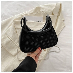 Détail du sac croissant noir à strass avec chaîne métallique et élégante tenue à la main