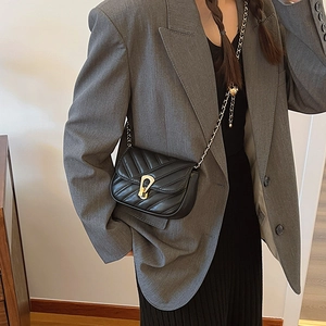 Quilted black leather crossbody bag with gold U-shaped buckle and metal chain strap