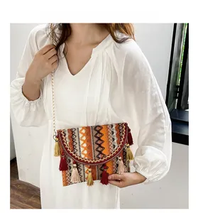 Detail of bohemian ethnic woven crossbody bag with colorful tassels and gold chain strap