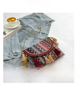 Detail of bohemian woven crossbody bag with colorful tassels and a gold chain strap