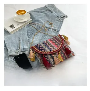 Detailed view of ethnic woven crossbody bag with colorful tassels and golden metal chain
