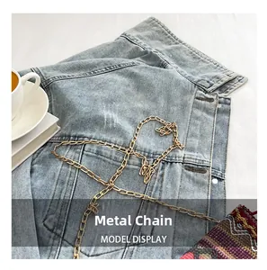 Detailed view of glossy gold metal chain accessory styled on a denim jacket garment