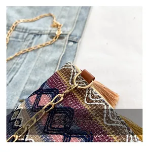 Detail of bohemian woven bag featuring geometric patterns, colorful tassels and gold hardware